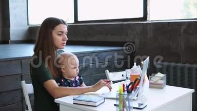 女商人正拿着婴儿在笔记本电脑前的贴纸上做笔记